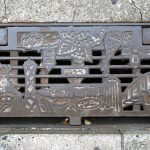 Grille d'évacuation des eaux présentant des lieux et figures emblématiques de Kobe