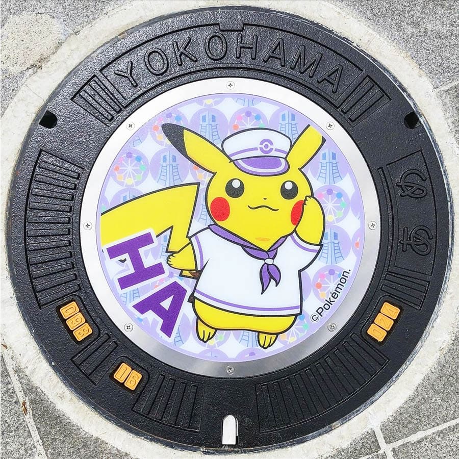 PokéPlak avec Pikachu matelot et le Yo de Yokohama sur un fond violet à motifs de grande roue et de tour